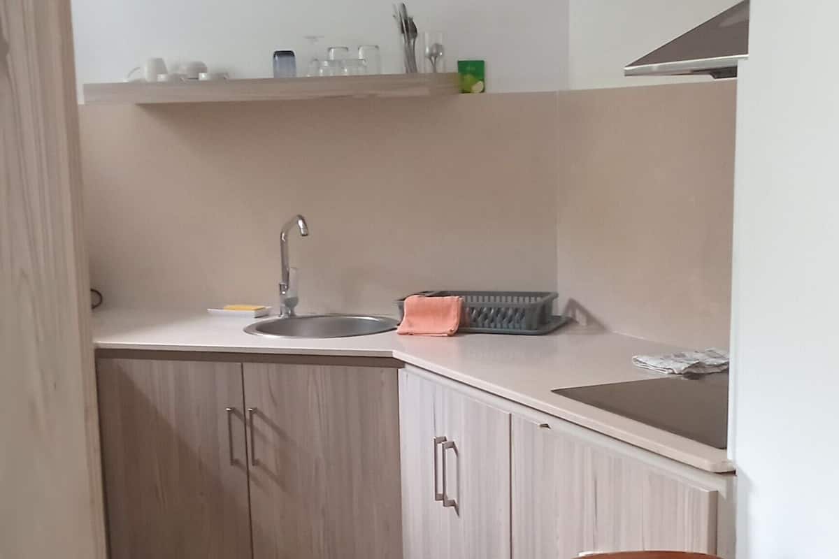 Une cuisine équipée d’un évier, de placards et d’un coin repas avec une table et des chaises.