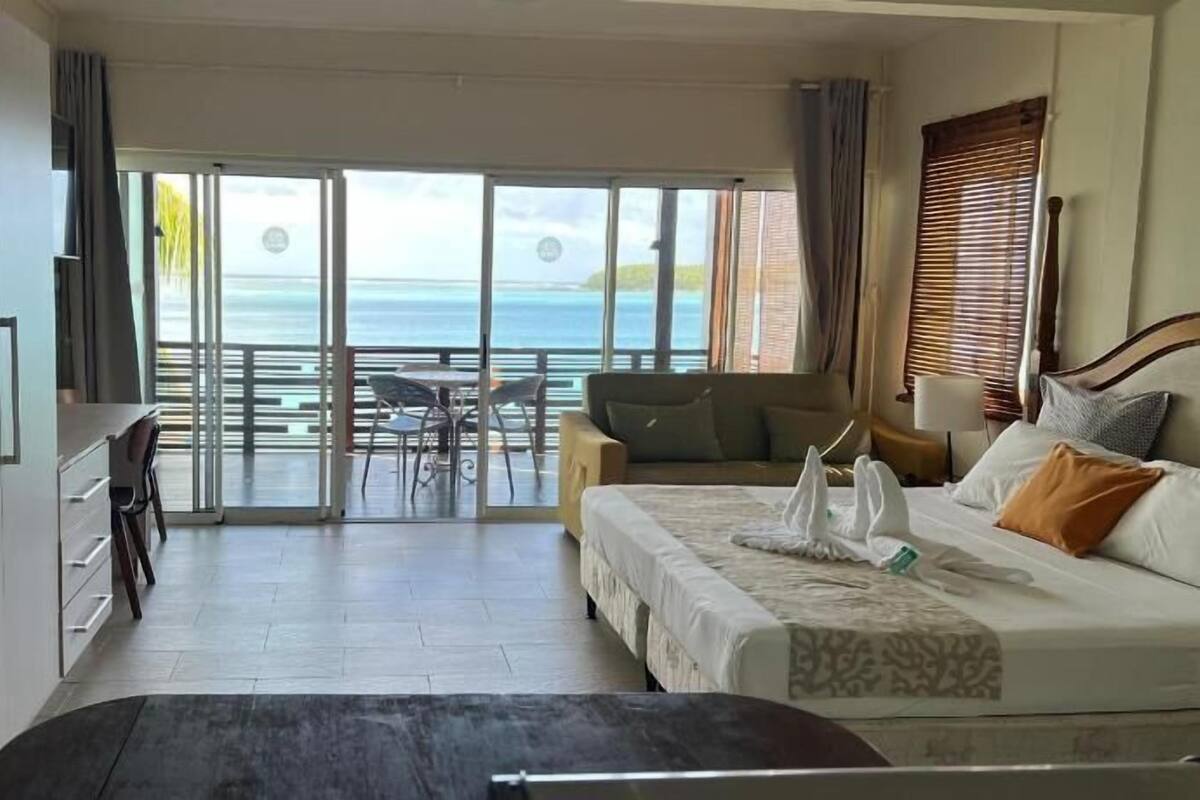 Une chambre d’hôtel avec un balcon, un lit, un bureau et une chaise.