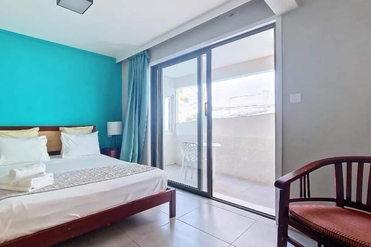 Une chambre d’hôtel avec un lit, une chaise, une table de chevet et une vue sur l’extérieur.