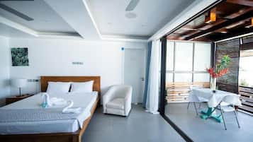 Una habitación de hotel moderna con una cama grande, un área de descanso con una mesa y vistas a través de un ventanal.