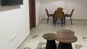 A modern dining area with a round table, chairs, a TV mounted on the wall, and a patterned floor. - One bedroom + living room in Diamniadio confort (Diamniadio)