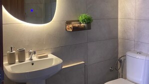 A bathroom with a modern design, featuring a large mirror, a sink, a toilet, and a small plant on the wall. - One bedroom + living room in Diamniadio confort (Diamniadio)
