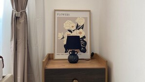 A bedside table with a framed picture, a small vase, and a drawer. - One bedroom + living room in Diamniadio confort (Diamniadio)