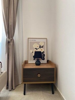 Ein Nachttisch mit gerahmtem Bild, kleiner Vase und einer Schublade.