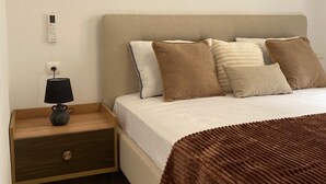 A bedroom with a bed, nightstand, lamp, and a wall socket. - One bedroom + living room in Diamniadio confort (Diamniadio)