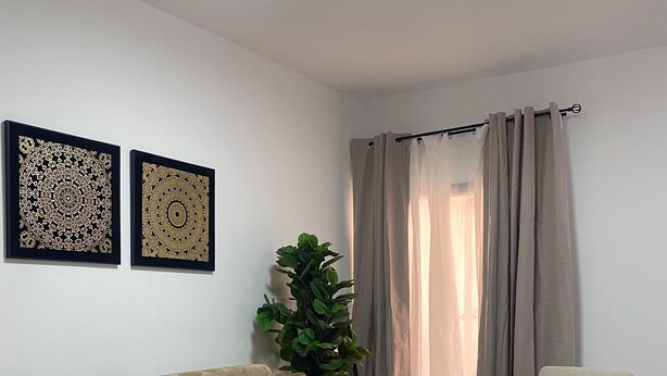 A living room with a sofa, armchair, two coffee tables, a potted plant, and two framed wall art pieces. - One bedroom + living room in Diamniadio confort (Diamniadio)