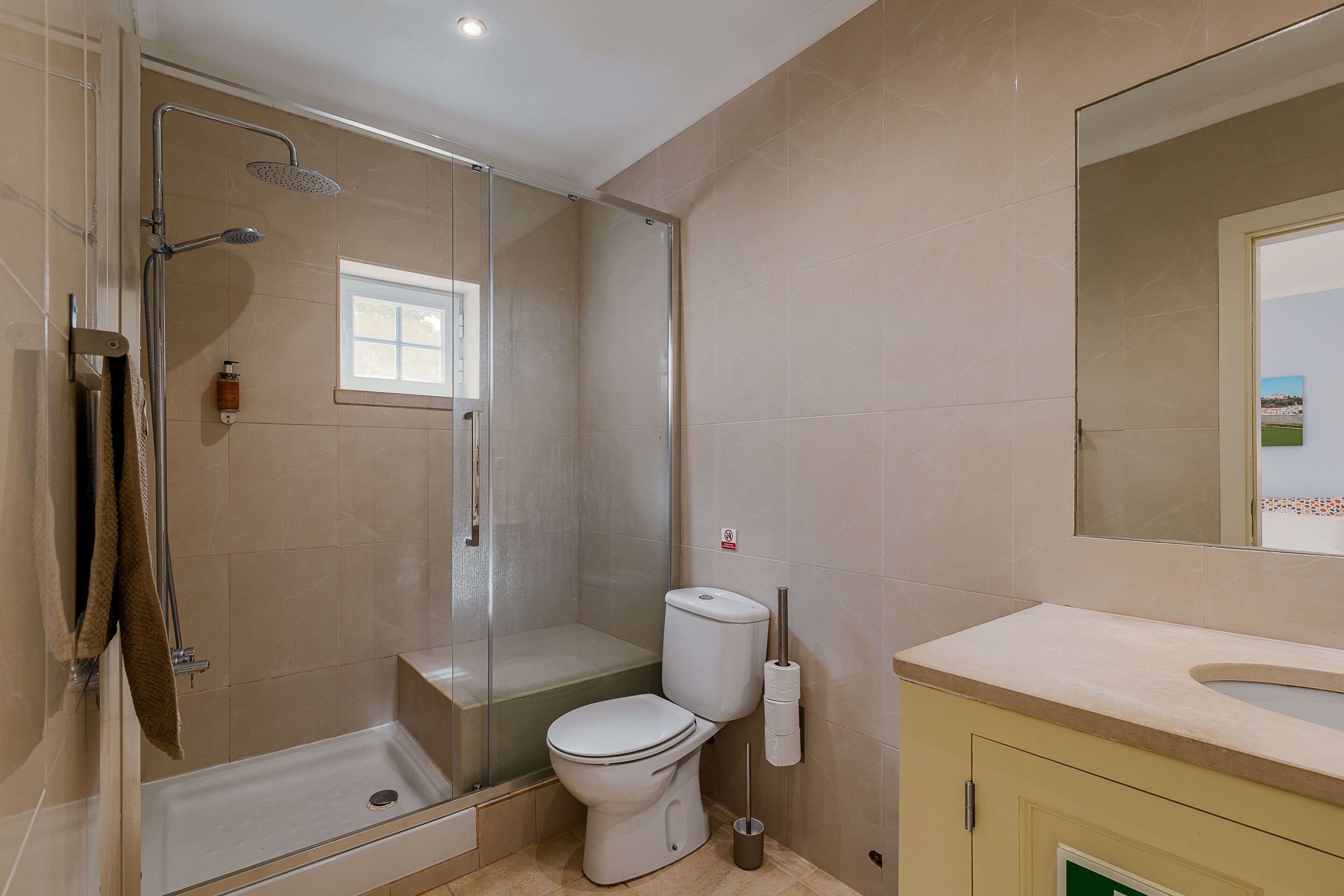 Een badkamer met douche, toilet en wastafel.