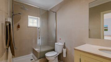 Een badkamer met douche, toilet en wastafel.