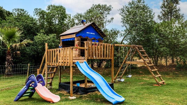 Una struttura di gioco in legno con scivolo e elementi da arrampicata.