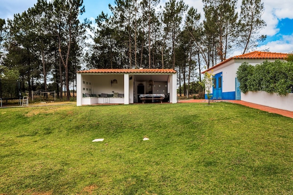 Un edificio con techo de tejas rojas, un espacio cubierto al aire libre y una pared exterior blanca.