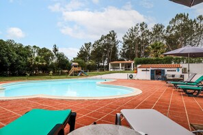 Piscina con tobogán, mobiliario exterior y zona cubierta.