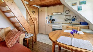 Une pièce de style « loft », avec un escalier en bois, une table à manger et un coin cuisine.