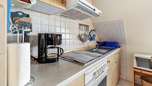 Une cuisine équipée d’une cuisinière, d’une machine à café et de divers ustensiles.