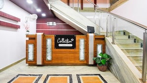 Una mesa de recepción con un cartel que dice 'Collection', una escalera y una planta en maceta.