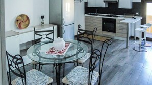 A modern kitchen with a dining area, including a glass table, chairs, and a refrigerator. - Blue Nest Ottava (Sassari)