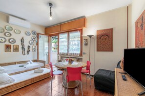 Una habitación con una cama, una mesa de comedor con sillas, un televisor y un ventanal con cortinas.