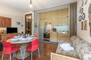Un espacio habitable compacto con zona de comedor, kitchenette y sofá.