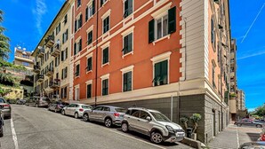 Un immeuble à plusieurs étages, avec une rangée de voitures garées le long de la rue.