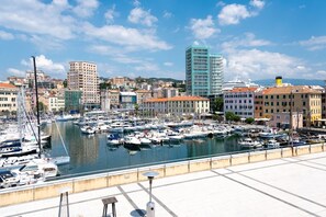 A marina with numerous boats docked, surrounded by buildings and a clear sky. - [Center Refuge] Free Parking • Garden • Cruises (Savona)