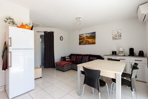 Un espace de vie compact comprenant un coin cuisine, un coin repas et un canapé.