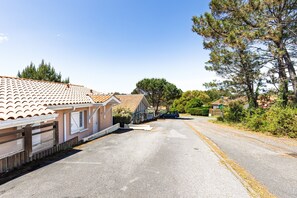 Une rangée de maisons de plain-pied avec des toits en tuiles, une allée pavée et un ciel dégagé.