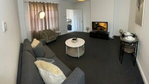 A modern living room with a sofa, a coffee table, a TV, and a dining area with a table and chairs. - Apartment Sleeps 2 - Free Street Parking (Gateshead)
