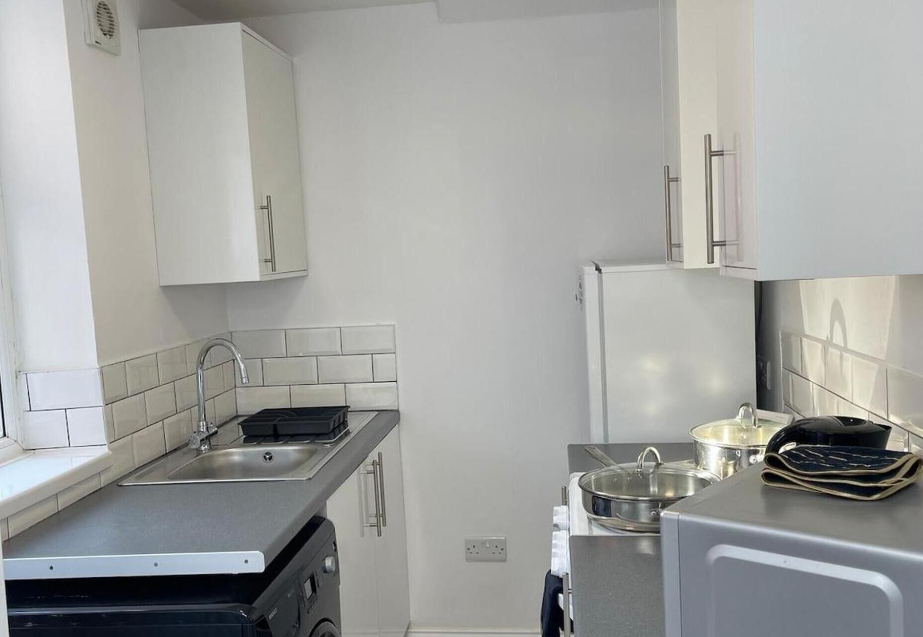 Eine kleine Küche mit Spüle, Herd und Kühlschrank.