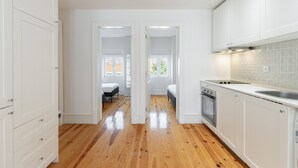 A modern kitchen with white cabinets, a stainless steel sink, and a wooden floor. - Graça Duplex With A View by Homing (Lisbon)