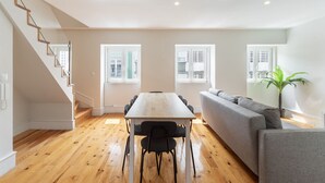 A modern interior with a dining table, chairs, a sofa, and a staircase. - Graça Duplex With A View by Homing (Lisbon)