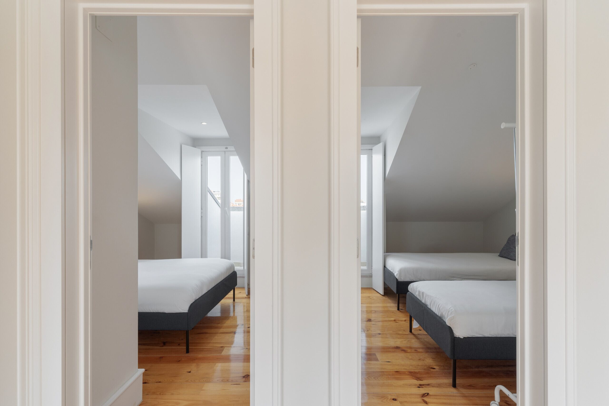 Un dormitorio con dos camas, piso de madera y techo inclinado.