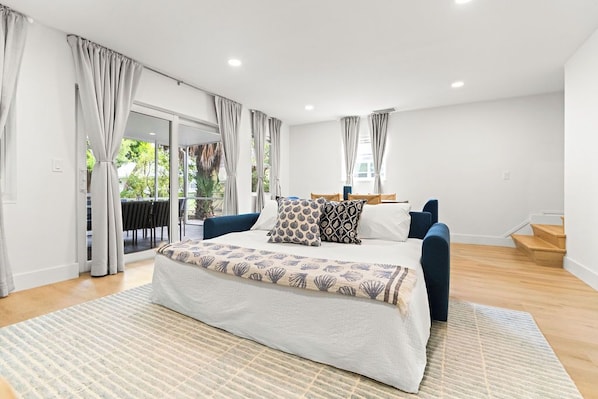 Ein Schlafzimmer mit Bett, einer Couch, einem großen Fenster und einer Treppe.