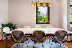 A dining area with a long table, four chairs, and hanging pendant lights. - Holiday Home 'Am Ritzberg' with Private Terrace, Shared Garden and Sauna (Beverungen)