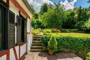 A building with a stone staircase leading to a garden with a hedge and a bench. - Holiday Home 'Am Ritzberg' with Private Terrace, Shared Garden and Sauna (Beverungen)