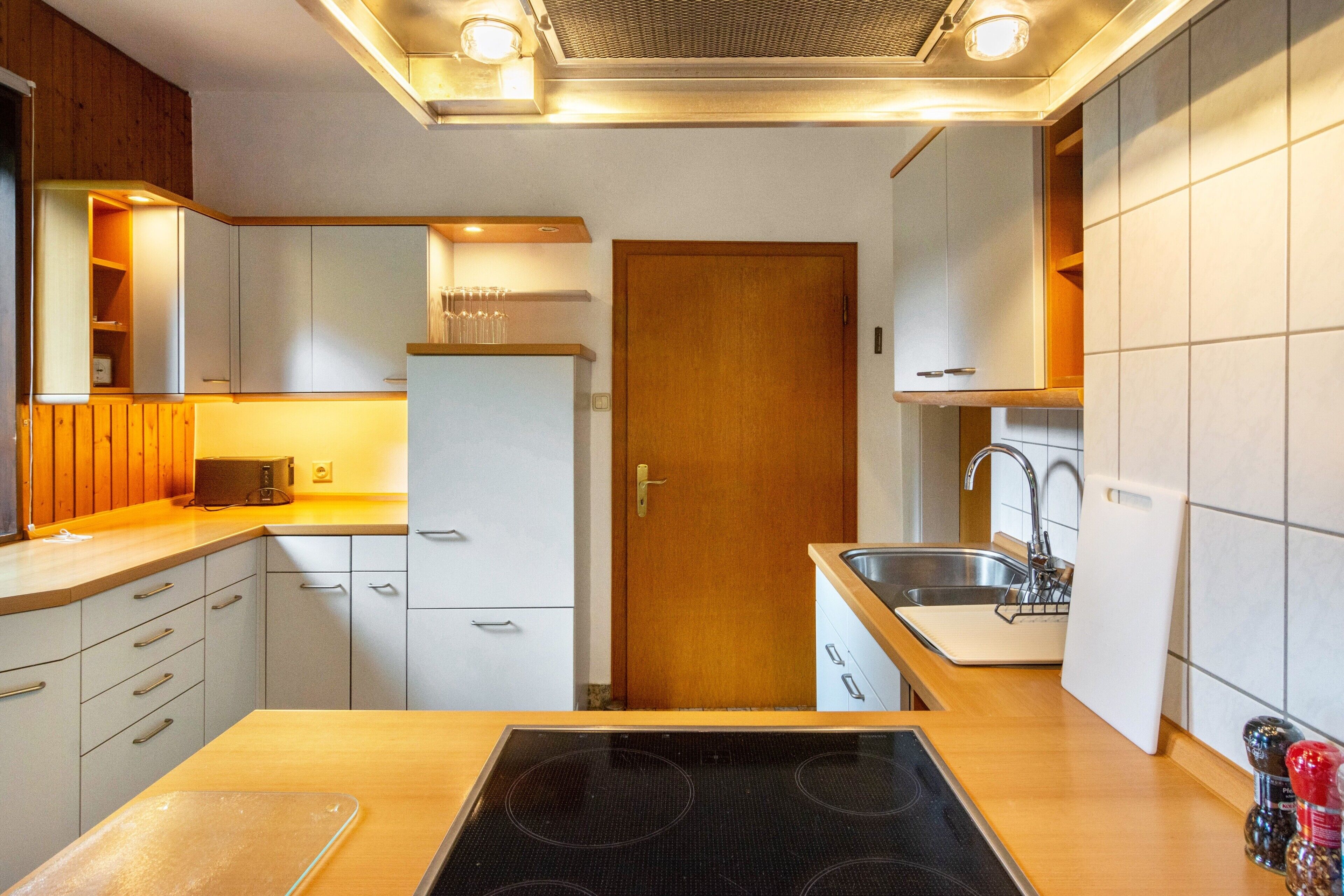 A compact kitchen with a built-in stove, a sink, and wooden cabinetry.