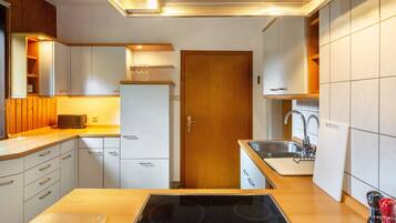 A compact kitchen with a built-in stove, a sink, and wooden cabinetry.