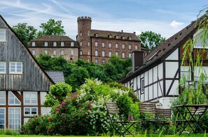 A traditional half-timbered building with a tower, surrounded by lush greenery and a garden with a bench. - Holiday Home 'Am Ritzberg' with Private Terrace, Shared Garden and Sauna (Beverungen)