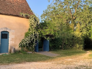 Ein rustikales Gebäude mit blauer Tür, einem steinernen Bogen und einem Garten mit einem Weg.