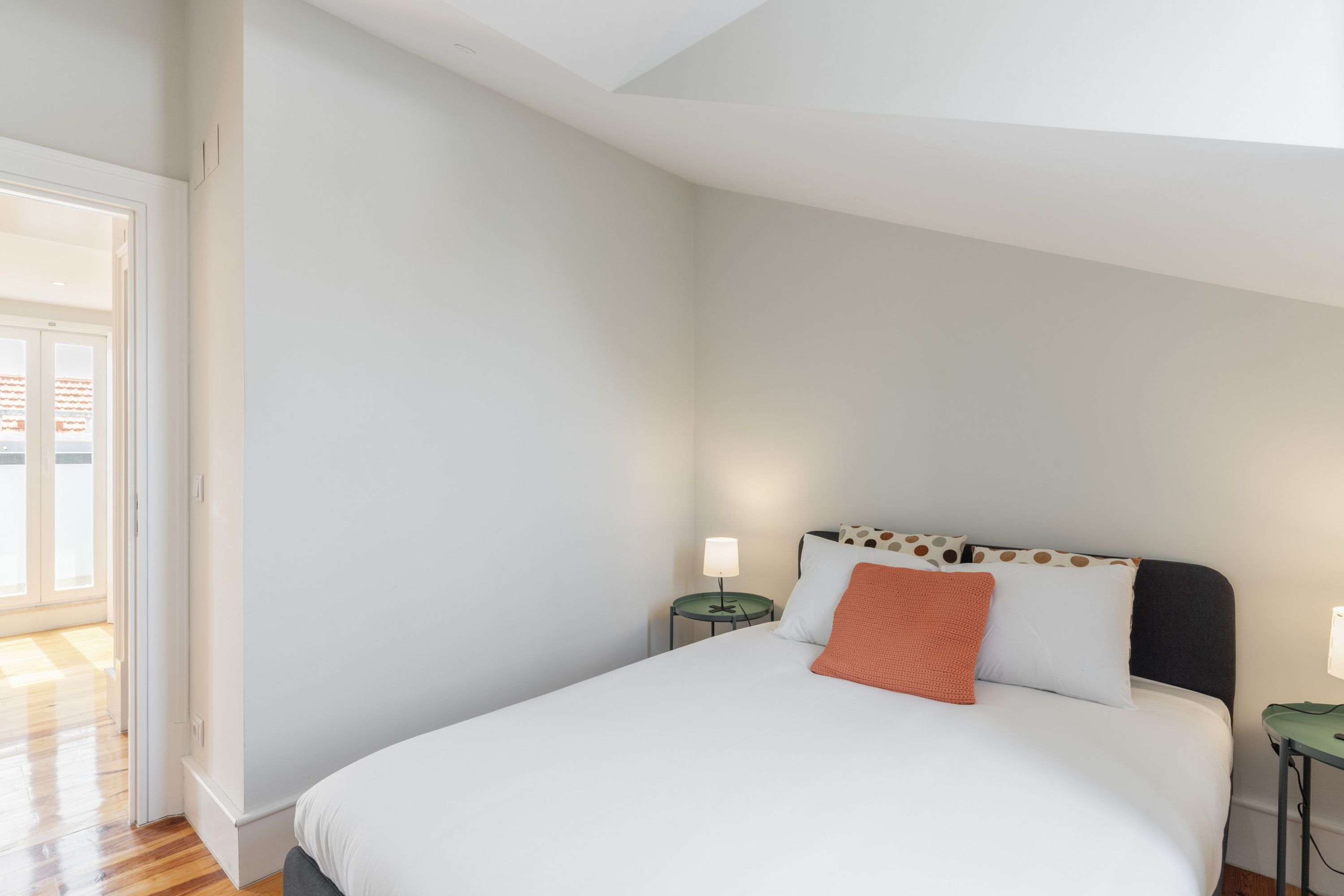 Une chambre à coucher comprenant un lit, deux tables de chevet et une porte donnant sur un balcon.