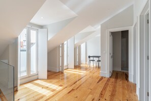 A spacious room with wooden flooring, large windows, and a high ceiling. - GRA A Duplex With A View by Homing (Lisbon)