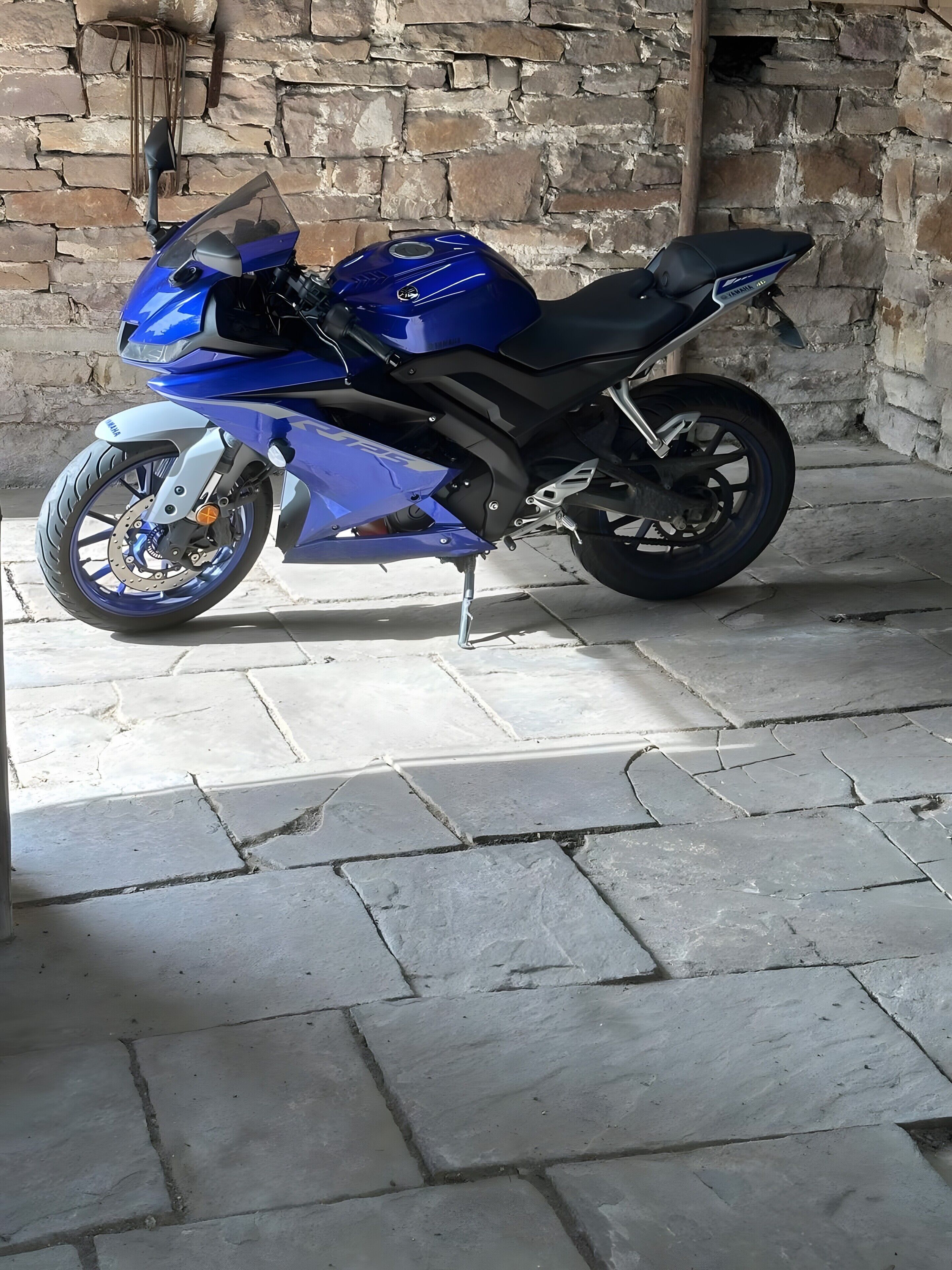 A motorcycle parked indoors with a stone wall background.