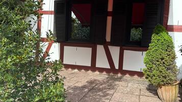 Ein traditionelles Gebäude mit einem Ziegeldach, einer roten Markise und einem kleinen Blumentopf.