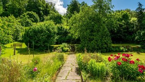 A stone pathway leading through a lush garden with a bench and a gate. - Holiday Home "Am Ritzberg 2" with Shared Garden and Wi-Fi (Beverungen)