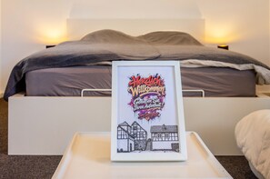 Velkomstskilt i ramme med illustration af et hus på et natbord i et hotelværelse.