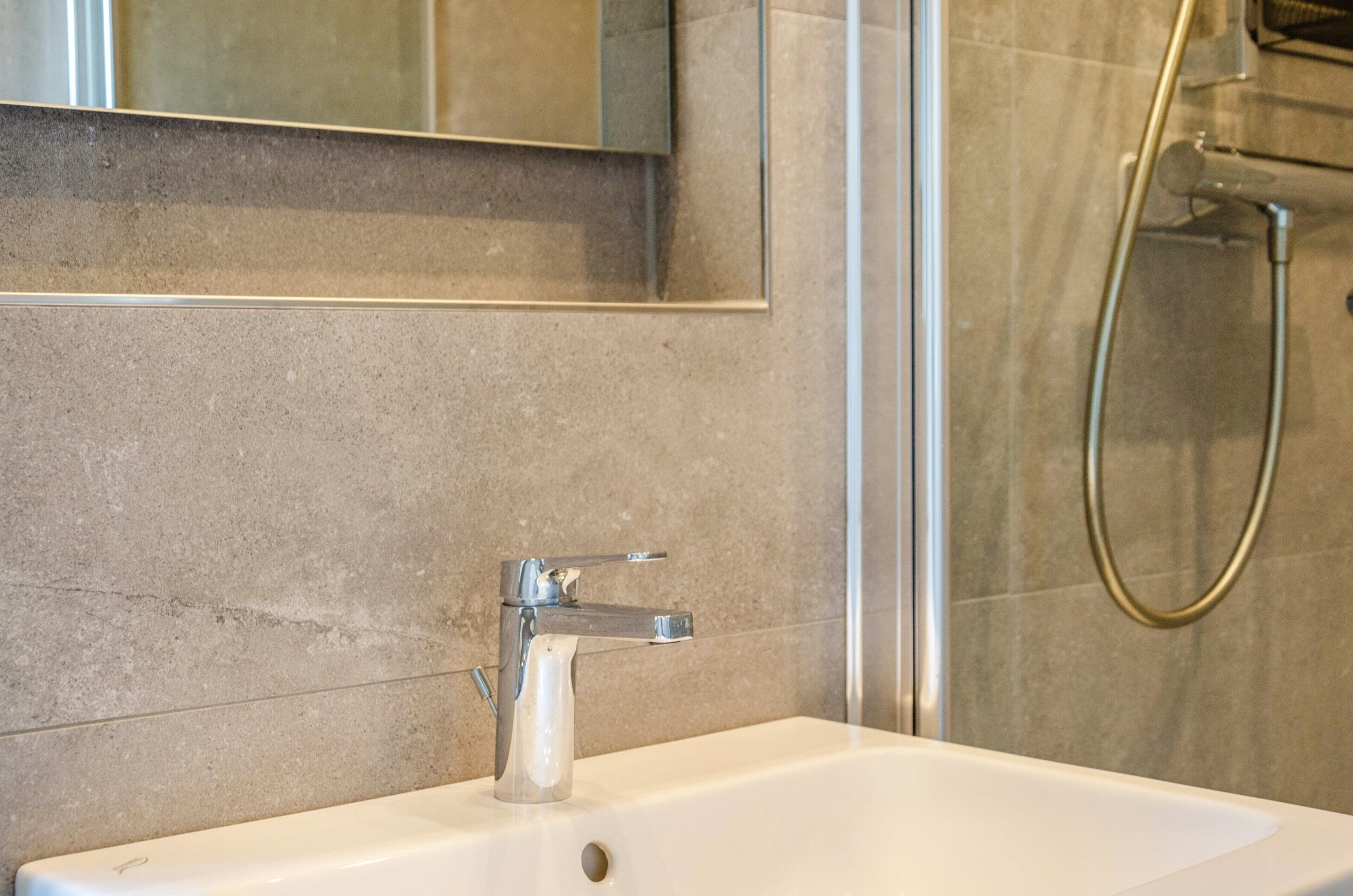 A bathroom with a white sink, a mirror, and a shower.