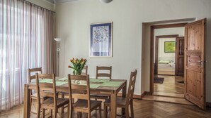 Ein Essbereich mit einem Holztisch und Stühlen, einer Vase mit Blumen und einem gerahmten Bild an der Wand.