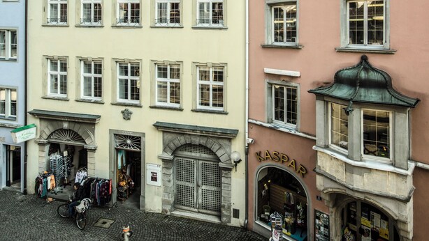 Ein Gebäude mit mehreren Fenstern, einem Schaufenster und einem Schild mit der Aufschrift 'KASPAR'.