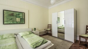 Ein Schlafzimmer mit Bett, Nachttisch, Stuhl, Kleiderschrank und einem Bild an der Wand.