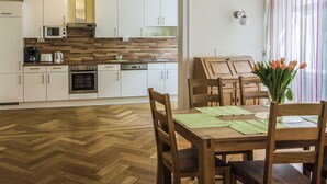 Eine moderne Küche mit weißen Schränken, einer Mikrowelle und einem Holzboden im Fischgrätmuster.