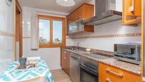 Cocina compacta con estufa, horno, microondas y ventana con cortinas.