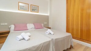 Una cama doble con dos almohadas, un armario de madera y dos cuadros en la pared.